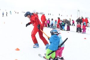 Skilehrer zieht zwei Kinder durch den Parcours
